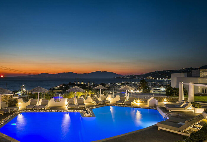 Ilio Maris hotel pool in Mykonos Town at sunset. Luxury gay honeymoon hotels offer stunning views. Perfect for LGBTQ+ travel & relaxation.