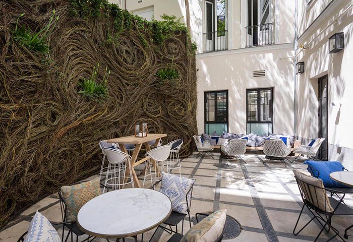 Only YOU Boutique Hotel Madrid outdoor seating area. Stylish tables, chairs, and a unique living wall in Chueca Gayborhood.