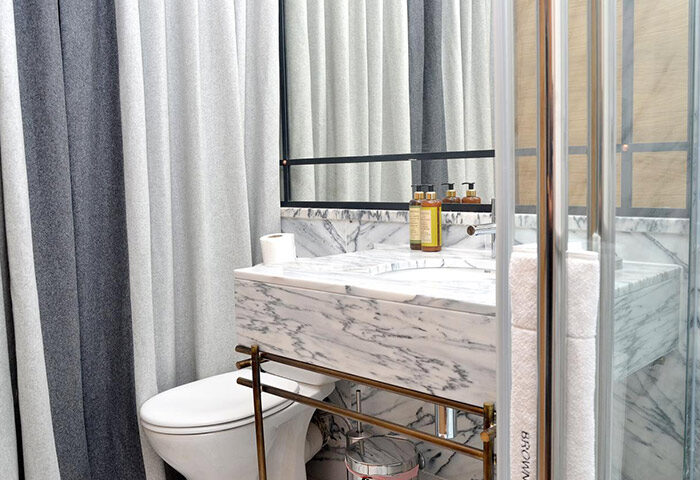 Browns Boutique Hotel Lisbon bathroom. Marble sink, shower, toilet, and striped curtains. Gay-friendly hotel with cheap price options.