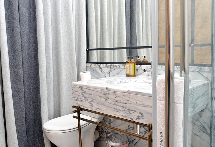 Browns Boutique Hotel Lisbon bathroom. Marble sink, shower, toilet, and striped curtains. Gay-friendly hotel with cheap price options.