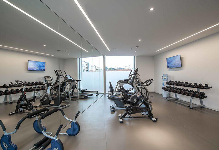 BessaHotel Liberdade gym. Lisbon gay hotel with cheap price offers fitness center. Exercise equipment, weights, and TVs in modern space.
