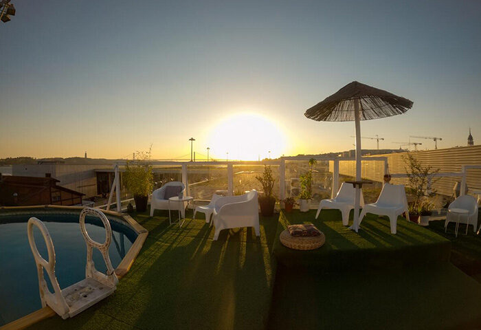 Sunset Destination Hostel rooftop pool in Lisbon's gayborhood. Cheap price hostel with sunset view, pool, chairs, and umbrella.