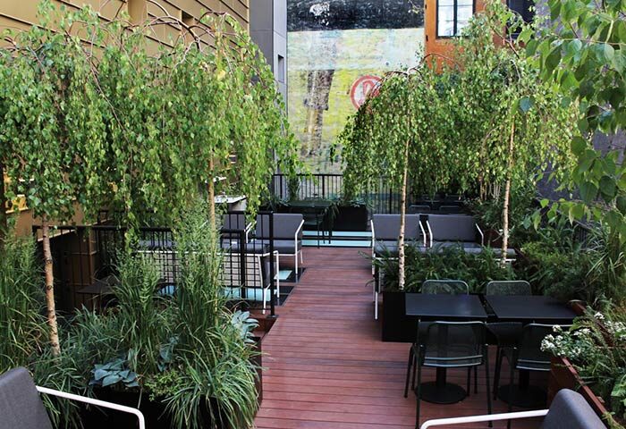 Hotel Herman K by Brøchner Hotels rooftop garden in Nyhavn. Luxury gay hotel with seating, tables, and lush greenery. Perfect for gay travel.