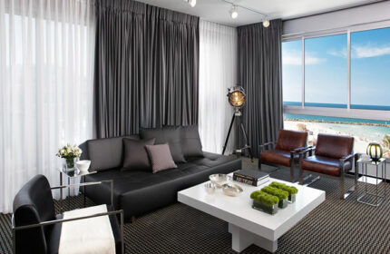 Alexander Tel Aviv Hotel room for 5 people. Upscale gay hotel beachfront view. Modern design, sofa, chairs, and beach view.