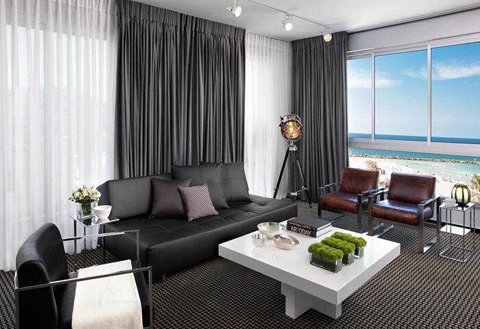 Alexander Tel Aviv Hotel room for 5 people. Upscale gay hotel beachfront view. Modern design, sofa, chairs, and beach view.