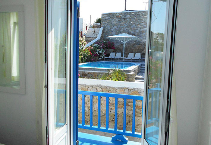 Mykonos gay hotel: Private pool view from Portobello Boutique Hotel room. Blue balcony, sunbeds, umbrella. Find cheap villas for group of friends.
