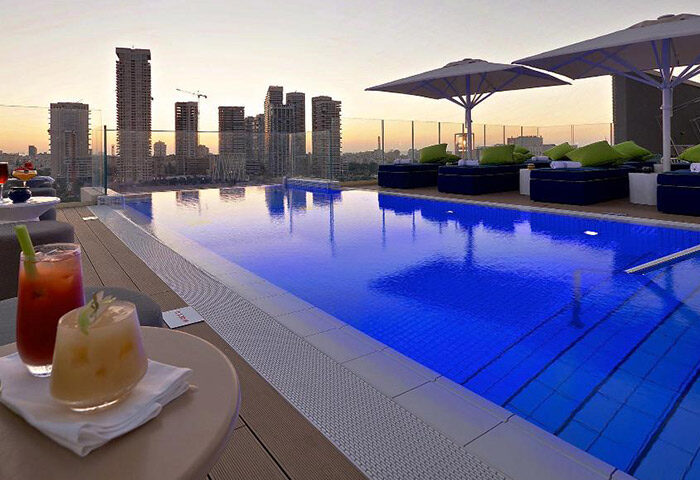 Hotel Indigo Tel Aviv rooftop pool at sunset. Upscale gay hotel in Diamond District. Cocktails, city view.