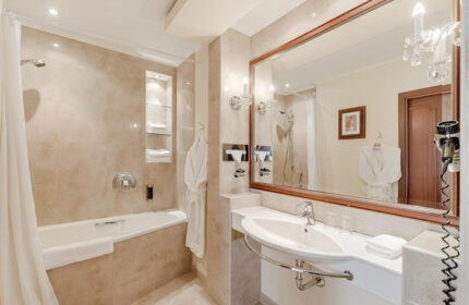 Louren Hotel bathroom in Prague's gayborhood, Vinohrady. Bathtub, sink, mirror, and robe offer a luxurious experience for gay travelers.