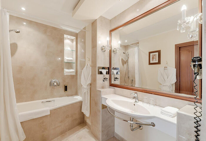 Louren Hotel bathroom in Prague's gayborhood, Vinohrady. Bathtub, sink, mirror, and robe offer a luxurious experience for gay travelers.