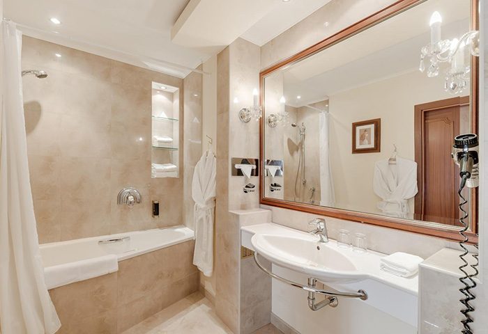 Louren Hotel bathroom in Prague's gayborhood, Vinohrady. Bathtub, sink, mirror, and robe offer a luxurious experience for gay travelers.