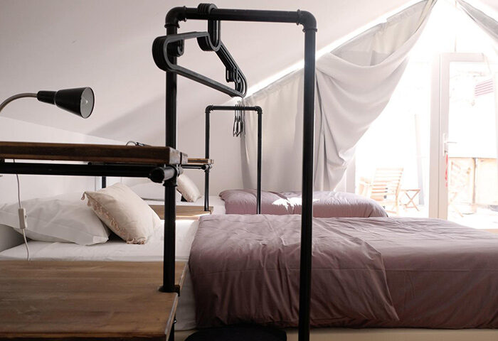 Lisbon Poets Inn Hostel bedroom for 3 people. Gay-friendly hotel room in Lisbon gayborhood. Industrial design with metal pipe clothes rack.