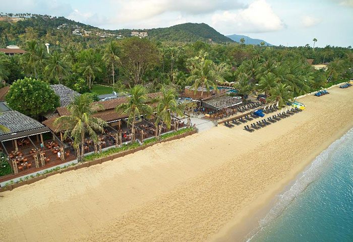 Bandara Resort & Spa, Koh Samui. Beachfront hotel view, palm trees, restaurant, and beach chairs. Gay-friendly hotels for last-minute trips.