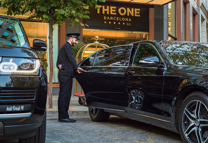 Luxury gay hotel H10 The One Barcelona: Doorman opening car door. Upscale Eixample area hotel offers last minute cheap price deals.