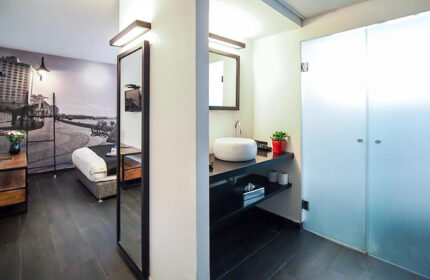 Dizengoff Avenue Boutique Hotel room. Modern design, sleek bathroom, and Tel Aviv cityscape mural. Gay-friendly hotel for 3 people.