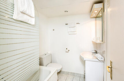 Hotel Dwin bathroom. Find last minute gay hotel in Marais gayborhood Paris. All-white bathroom with shower, sink, toilet, and mirror.