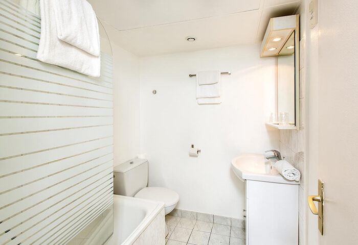 Hotel Dwin bathroom. Find last minute gay hotel in Marais gayborhood Paris. All-white bathroom with shower, sink, toilet, and mirror.