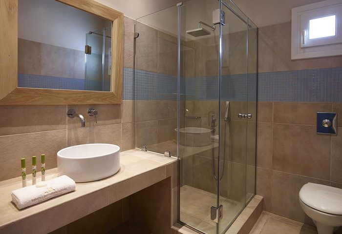 Mykonos City Center gay hotel bathroom at Vencia Boutique Hotel. Modern design with a shower, sink, mirror, and toilet. Find last minutes deals.