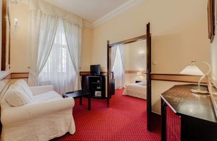 Louren Hotel room in Prague's Vinohrady. Find last minute gay hotels in Prague city center. Room with sofa, TV, and bedroom view. Interior design.