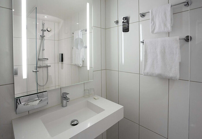 Scandic Copenhagen hotel bathroom. Modern design with white tiles, sink, mirror, and shower. Gay-friendly hotel in Vesterbro area. Last minute booking.