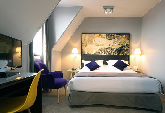 Little Palace Hotel room in Paris city center. Gay-friendly hotel with a bed, desk, chair, and modern decor. Find last minute deals!