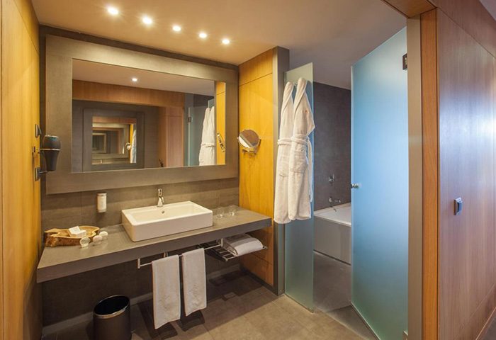 Lopesan Baobab Resort gay hotel bathroom. Modern sink, mirror, and bathrobes. Luxury Meloneras gay travel destination.