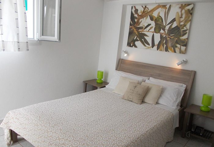 Mykonos Matina Hotel bedroom. Quiet, cheap gay hotel near gay party. Double bed, white walls, olive branch art. Last minute deals.