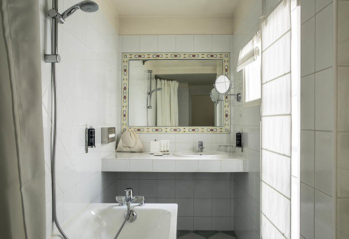 Hotel de la Place du Louvre bathroom. Find last minute gay hotel in Paris gayborhood. Sink, mirror, tub, and shower in a tiled bathroom.
