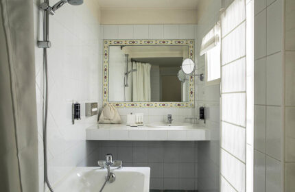 Hotel de la Place du Louvre bathroom. Find last minute gay hotel in Paris gayborhood. Sink, mirror, tub, and shower in a tiled bathroom.