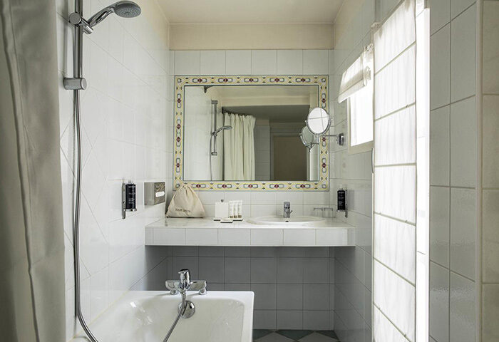 Hotel de la Place du Louvre bathroom. Find last minute gay hotel in Paris gayborhood. Sink, mirror, tub, and shower in a tiled bathroom.