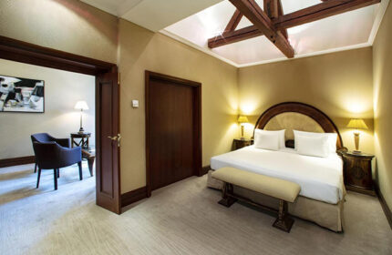NH Collection Carlo IV hotel room. Luxury gay hotels in Prague at cheap price. Bedroom with double bed, bench, and seating area.