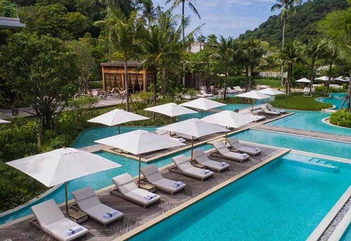 Rosewood Phuket luxury pool villas. Gay hotel in Phuket, Thailand. Cheap price. Tropical resort with pools, lounge chairs, and umbrellas.