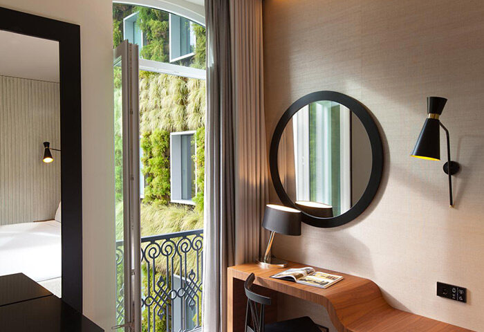 BessaHotel Liberdade stylish design. Minimalist room in Lisbon city center, desk, mirror, and balcony with green wall. Gay hotel travel.