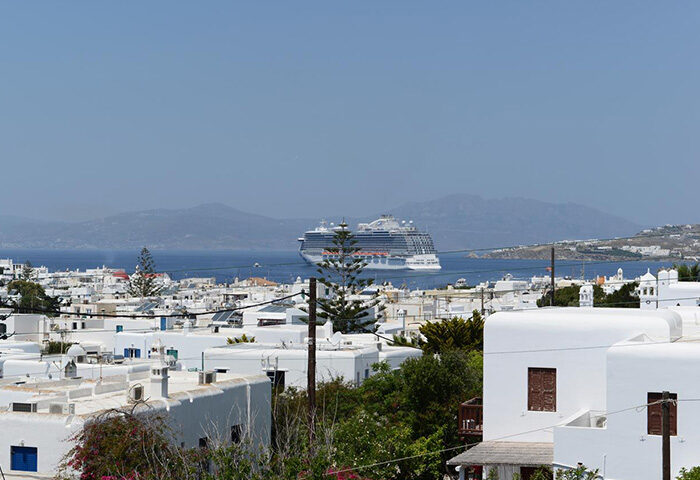 Mykonos Town view from Elena Hotel, a popular gay hotel near gay hotspots. Whitewashed buildings, cruise ship on the sea. Gayborhood.