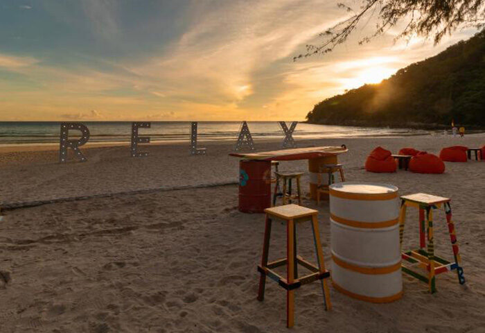 Le Meridien Phuket beachfront for gay honeymoon couples. RELAX sign, bar stools, and sunset. Top beachfront accommodation in Phuket.