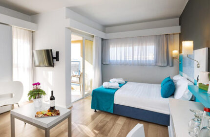 Prima City Tel Aviv Hotel triple room with balcony. Gay hotel room for 3 people with wine, fruit plate, and TV. Modern design.