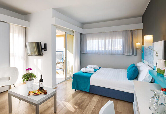 Prima City Tel Aviv Hotel triple room with balcony. Gay hotel room for 3 people with wine, fruit plate, and TV. Modern design.