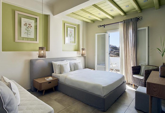 Vencia Boutique Hotel room in Mykonos Town. Find cheap prices on gay hotels. Room with bed, balcony, and green accents. Mykonos travel.