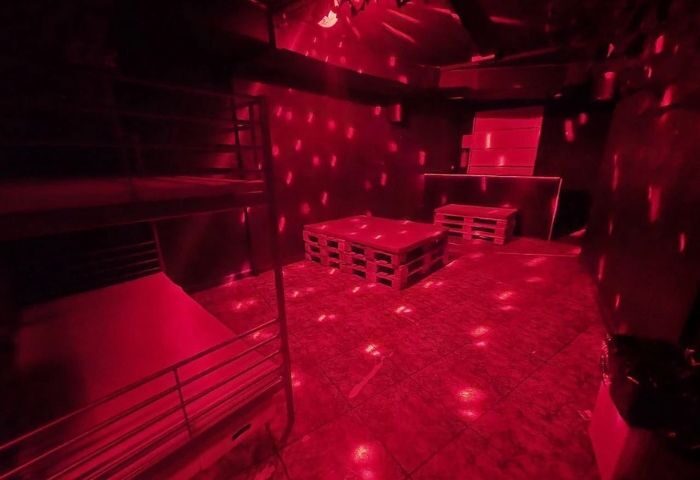 Inside Firewood Madrid, a gay cruise club: Red lighting, pallet tables, and a bunk bed create a unique, intimate space for gay men's travel.