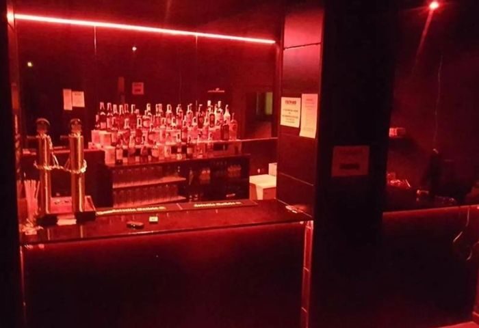 Interior of Firewood, a gay cruise club in Madrid. Bar with liquor bottles, red lighting. Gay Madrid nightlife travel advice.