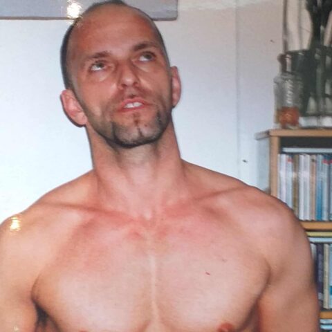 Gay massage spa in West London: shirtless fitness trainer/masseur looking up. Ideal for gay men's travel advice, relaxation, and wellness.