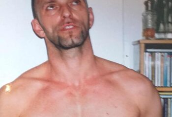 Gay massage spa in West London: shirtless fitness trainer/masseur looking up. Ideal for gay men's travel advice, relaxation, and wellness.