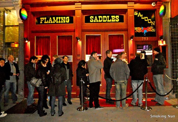 Flaming Saddles gay bar in New York City. Crowd waiting outside the popular gay saloon. Gay travel advice for NYC nightlife.