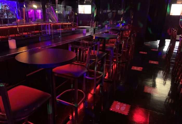 Interior of Flash on Church, a gay bar in Toronto. Tables and chairs line the dance floor. Red and purple lighting. Gay travel.