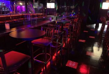 Interior of Flash on Church, a gay bar in Toronto. Tables and chairs line the dance floor. Red and purple lighting. Gay travel.