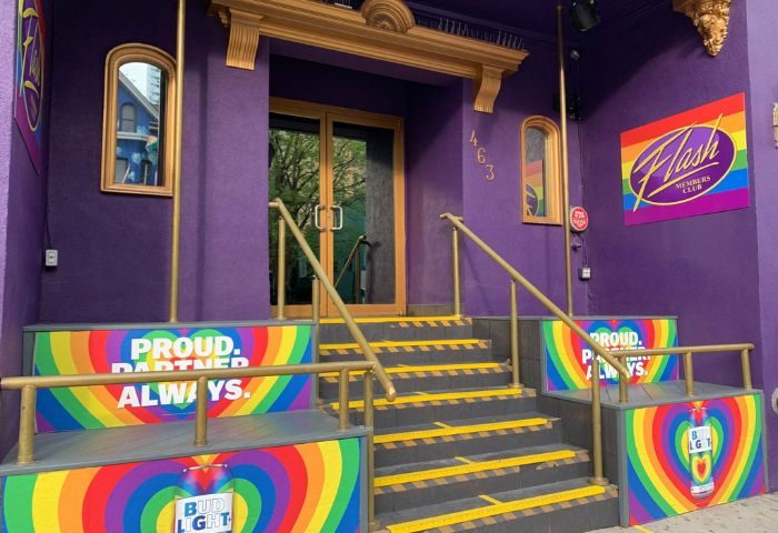 Flash on Church, a gay bar in Toronto. Purple building with rainbow decor. Proud Partnered Always and Bud Light logos. A vibrant LGBTQ+ destination.