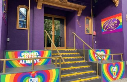 Flash on Church, a gay bar in Toronto. Purple building with rainbow decor. Proud Partnered Always and Bud Light logos. A vibrant LGBTQ+ destination.