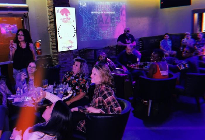 Flex Cocktail Lounge in Las Vegas: A diverse crowd enjoys drinks and entertainment in a dimly lit, stylish gay bar setting. Nightlife scene.