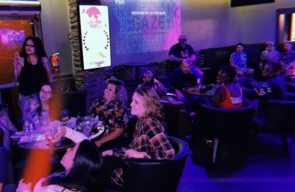 Flex Cocktail Lounge in Las Vegas: A diverse crowd enjoys drinks and entertainment in a dimly lit, stylish gay bar setting. Nightlife scene.