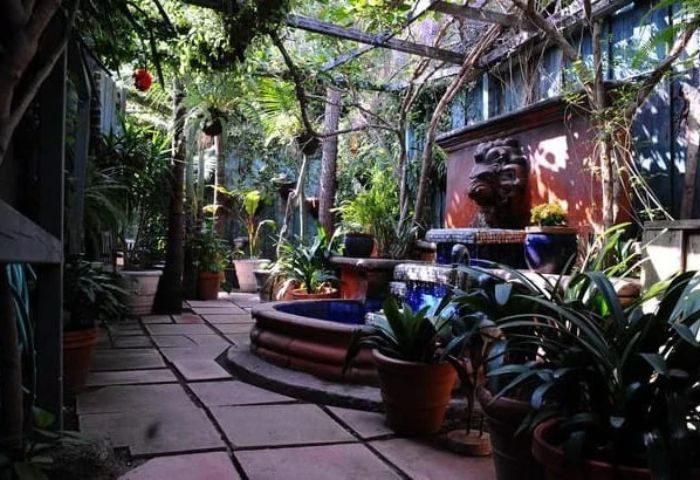 Flex LA Relaxation: Lush garden with a fountain, plants, and stone pathway. A peaceful, relaxing outdoor space for gay men's travel in LA.