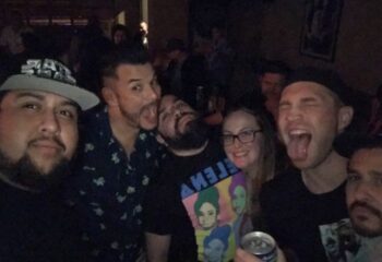 Gay men's travel: Group selfie at Flux Bar. Men and a woman smiling, sticking out tongues, and enjoying the Flux Bar experience. Nightlife.